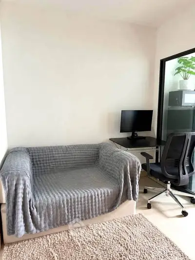 Cozy study area with modern desk, chair, and sofa in bright apartment corner.