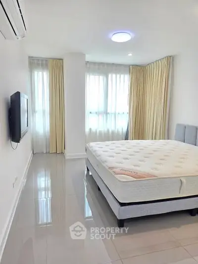 Spacious bedroom with natural light and modern decor in a luxury apartment.