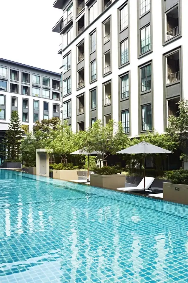 Luxurious apartment complex with a stunning outdoor pool and modern architecture.