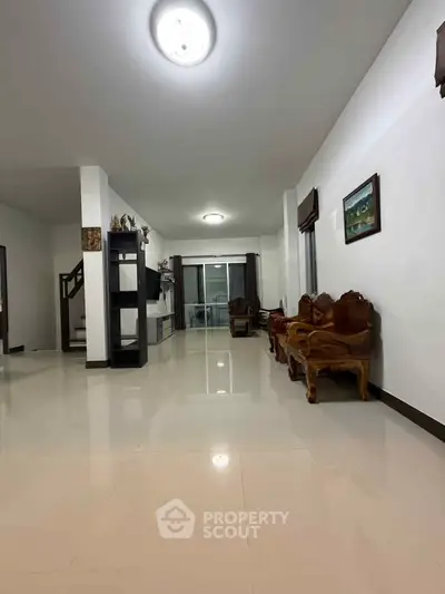 Spacious living room with elegant wooden furniture and glossy tiled flooring.