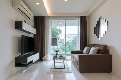 Modern living room with sleek furniture and large window offering a lush green view.