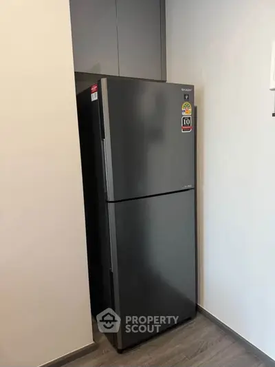 Modern kitchen with sleek stainless steel refrigerator in compact space.
