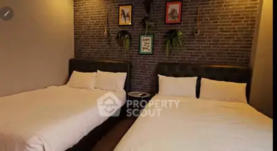 Cozy bedroom with two beds and stylish brick accent wall, perfect for relaxation.