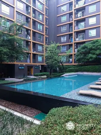 Luxurious residential complex with a serene pool area surrounded by lush greenery and modern apartment facades, offering a tranquil urban retreat.