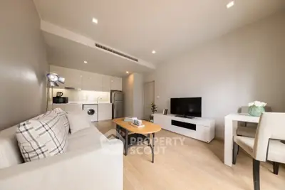 Modern living room with open kitchen, cozy sofa, and dining area in a stylish apartment.