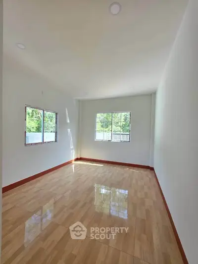 Spacious empty room with large windows and wooden flooring, perfect for customization.