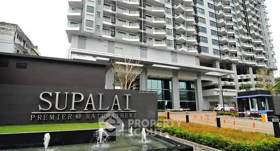 Modern high-rise building exterior with elegant entrance and water feature at Supalai Premier Ratchathewi.