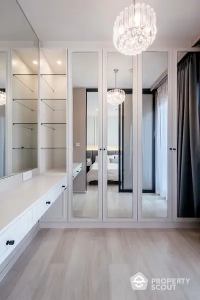 Luxurious bedroom with mirrored wardrobe and elegant chandelier lighting.