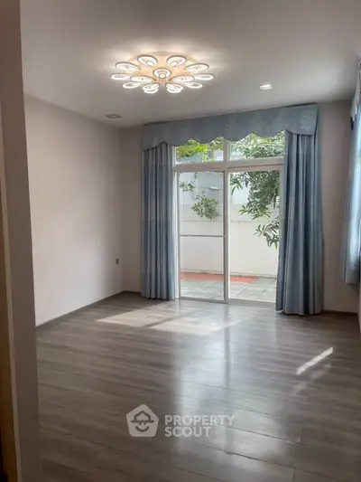Spacious empty living room with elegant chandelier and large window view.