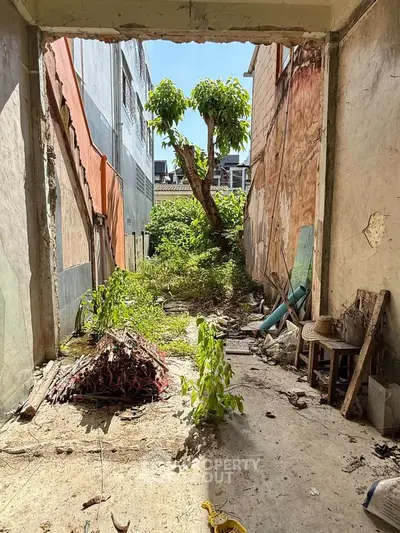 Dilapidated urban property with overgrown vegetation and exposed walls, ideal for renovation or redevelopment.