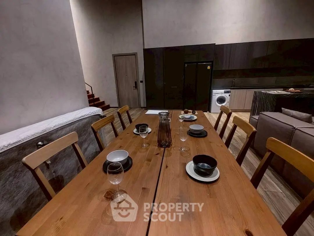 Modern dining area with wooden table, stylish kitchen, and cozy living space.