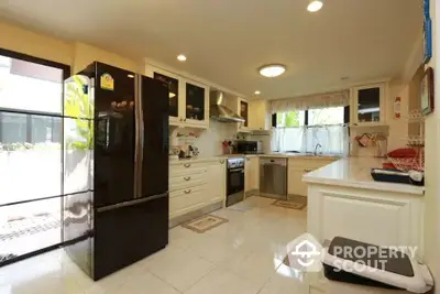 Spacious modern kitchen with sleek black fridge and ample natural light