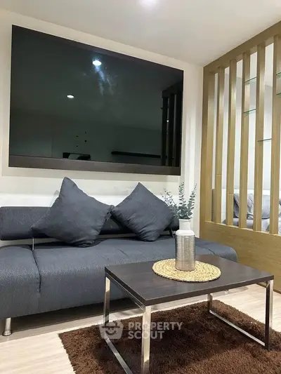 Modern living room with sleek sofa and large TV, perfect for relaxation and entertainment.