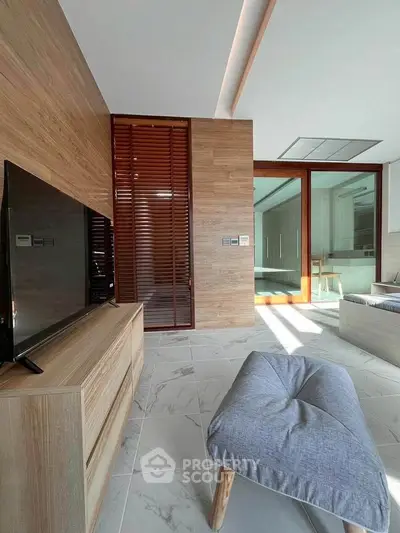 Modern living room with wooden accents and sleek furniture, featuring a large TV and stylish decor.