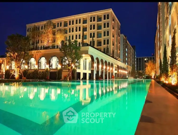 Luxurious apartment complex with illuminated pool and elegant architecture at night.