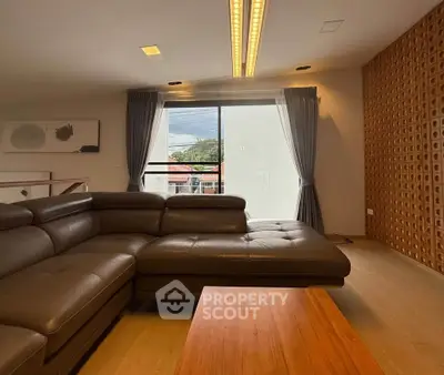 Spacious living room with modern leather sofa and large window view.