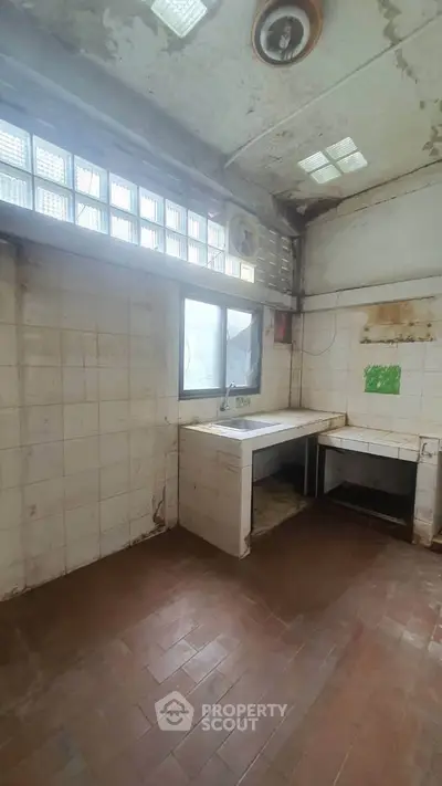 Spacious kitchen with large windows, tiled walls, and ample natural light, ideal for renovation.