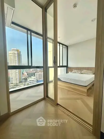 Modern bedroom with large windows offering stunning city views in a high-rise apartment.