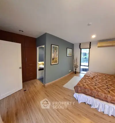 Spacious bedroom with wooden flooring and large window for natural light
