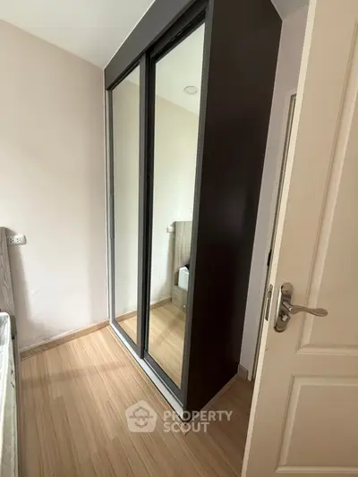 Modern bedroom with sleek mirrored wardrobe and wooden flooring