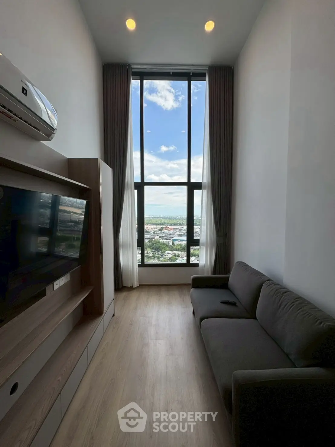 Modern living room with floor-to-ceiling window offering stunning city view