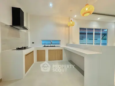 Modern kitchen with sleek design, featuring gas stove and stylish pendant lights.