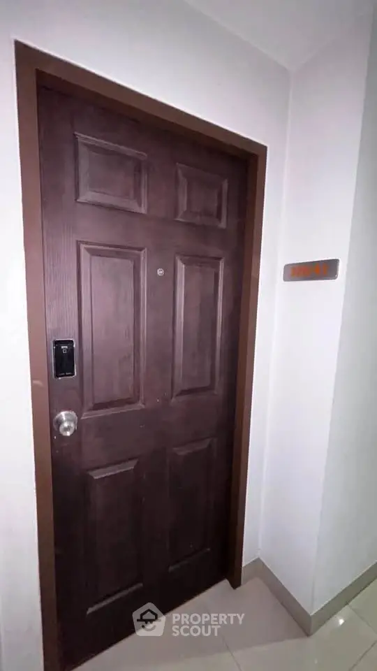 Sturdy wooden apartment door with modern electronic lock in a well-lit hallway.