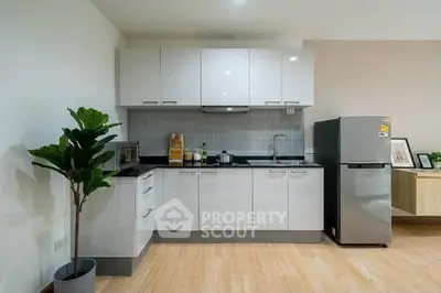 Modern kitchen with sleek cabinetry and stainless steel fridge in a stylish apartment.