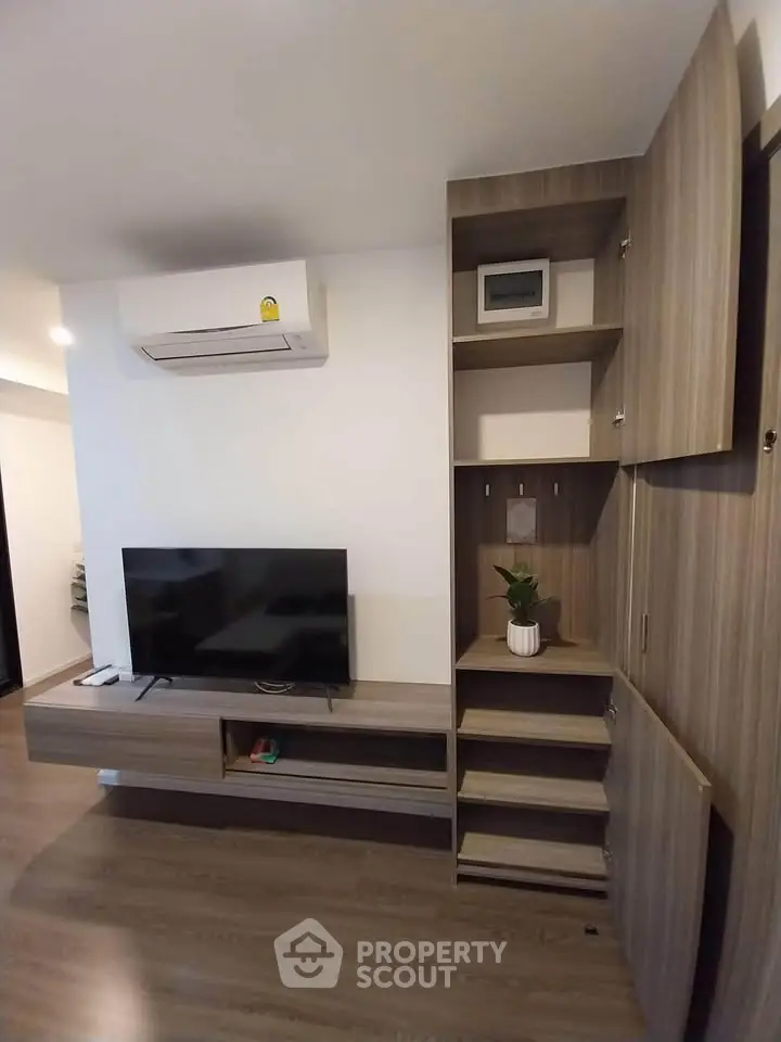 Modern living room with sleek wooden cabinetry and mounted TV, featuring air conditioning.