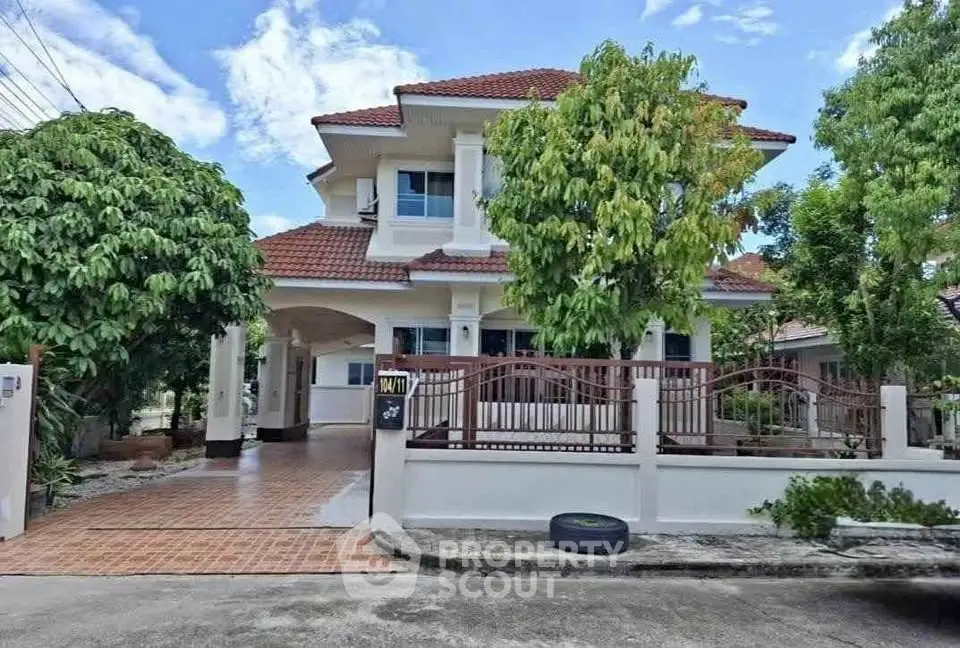 Charming two-story house with red-tiled roof and lush garden in a serene neighborhood.