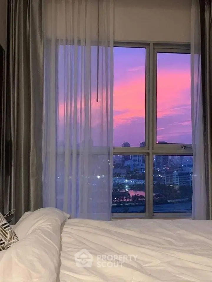 Stunning bedroom view with vibrant sunset over city skyline, perfect for urban living enthusiasts.