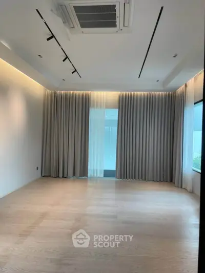 Spacious empty room with elegant curtains and modern ceiling lights, perfect for customization.