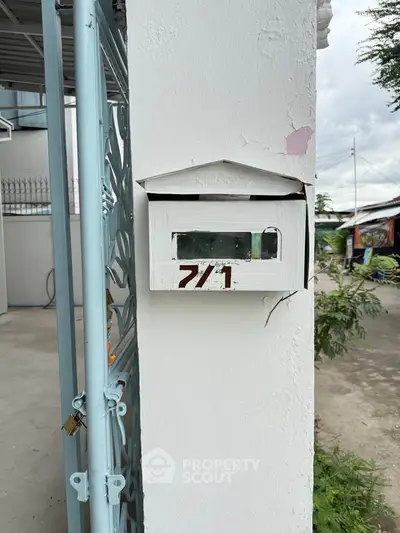 Charming mailbox on a white pillar at a residential entrance, perfect for a cozy home setting.