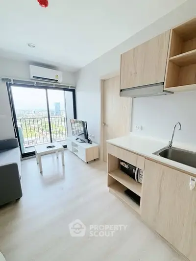 Modern living room with kitchenette and city view balcony in bright apartment.