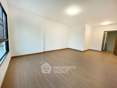 Spacious empty room with wooden flooring and large window