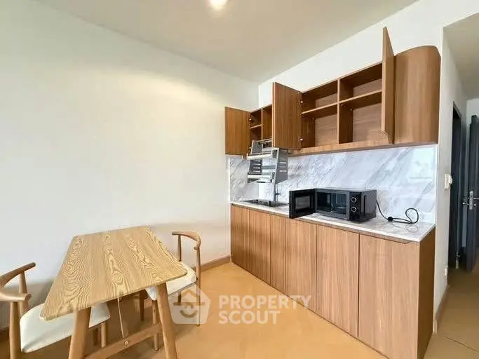 Modern kitchen with wooden cabinets and dining area in a cozy apartment.