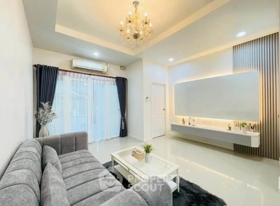 Elegant living room with modern chandelier and plush gray sofa, perfect for stylish living.