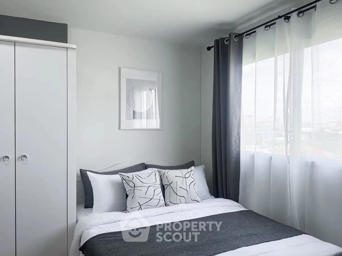 Modern bedroom with stylish decor and large window offering natural light.