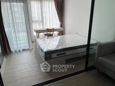 Modern bedroom with large windows and natural light, featuring a stylish bed and a cozy workspace.