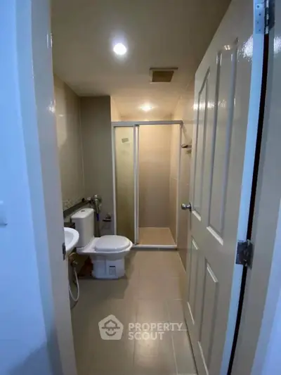 Modern bathroom with shower and toilet in a sleek apartment unit.