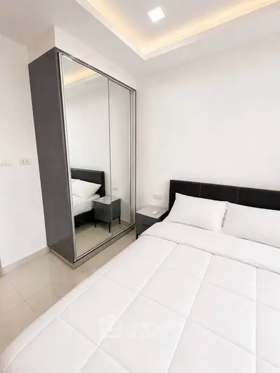 Modern bedroom with sleek mirrored wardrobe and cozy bed in minimalist design.