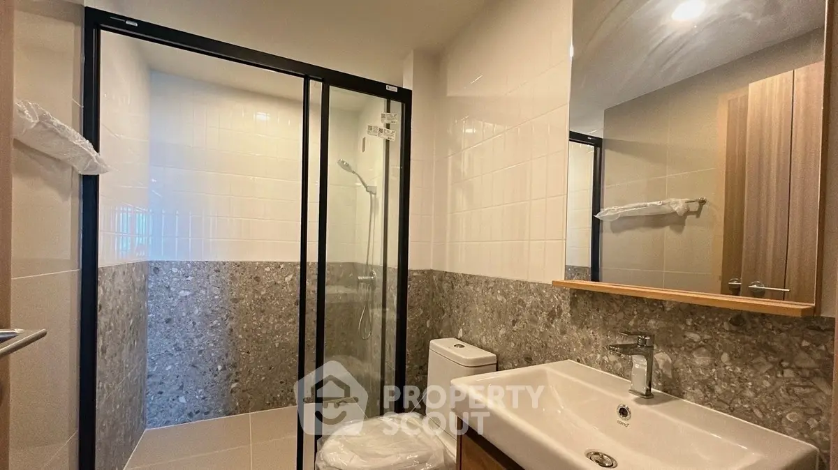 Modern bathroom with sleek shower and stylish sink in a contemporary apartment.