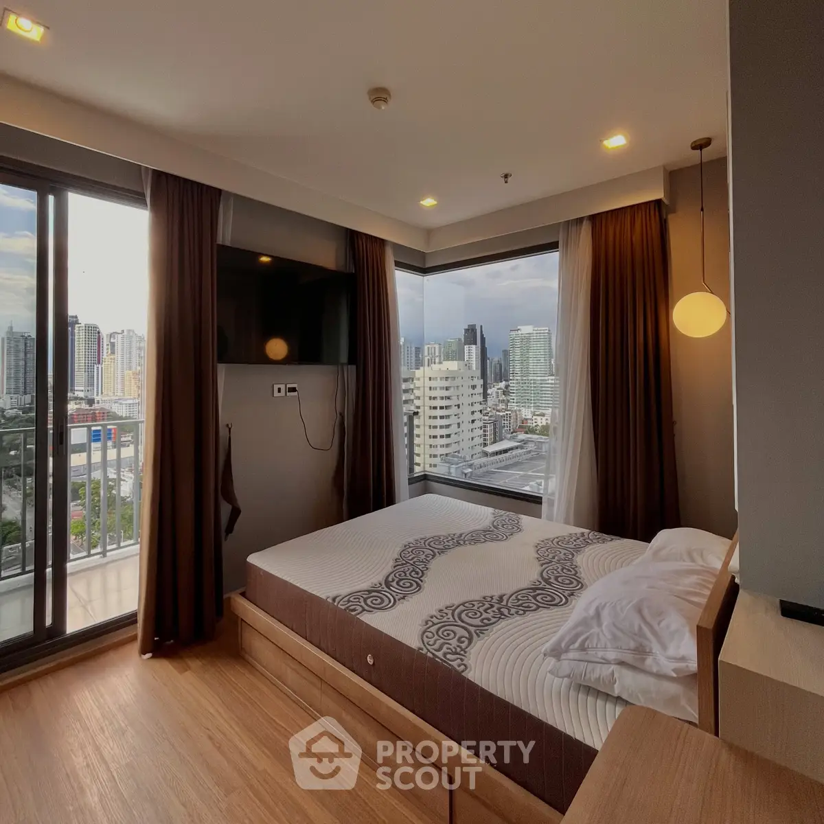 Modern bedroom with city view and balcony access in high-rise apartment