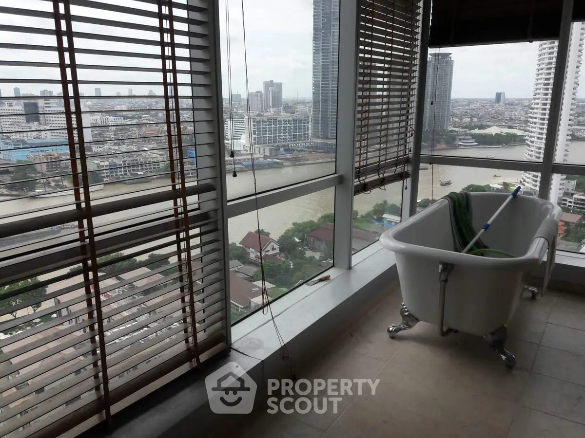 Luxurious high-rise balcony with stunning city and river views, featuring a unique standalone bathtub.