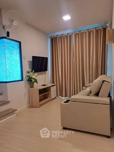 Cozy living room with modern decor, featuring a comfortable sofa, wall-mounted TV, and elegant curtains.