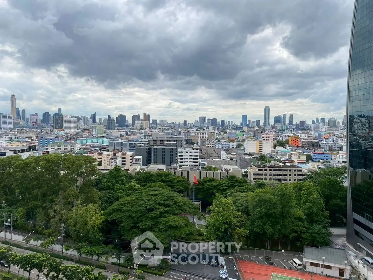 Stunning cityscape view from high-rise building with lush greenery and urban skyline.