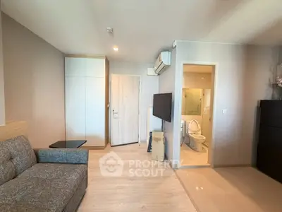 Modern living room with sleek design and open bathroom view, featuring a cozy sofa and wall-mounted TV.