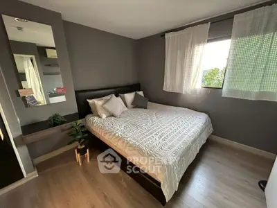 Cozy bedroom with modern decor and large window offering natural light.