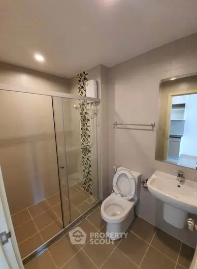 Modern bathroom with glass shower and sleek fixtures in contemporary apartment.