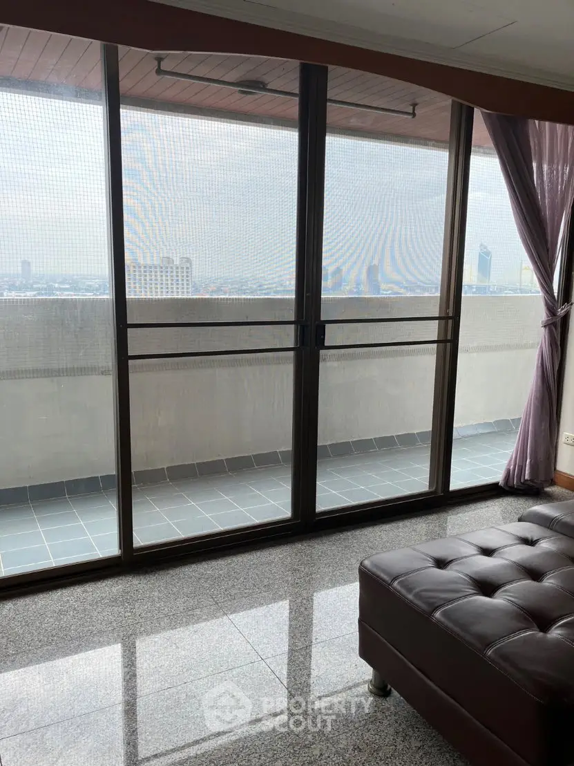 Spacious living room with large windows and balcony offering stunning city views.